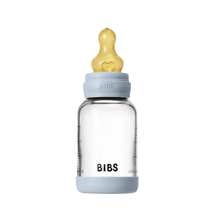 Clear baby bottle with gold nipple and blue cap on a white background