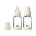 Two clear baby bottles with beige caps and 'Bibs' branding on a white background