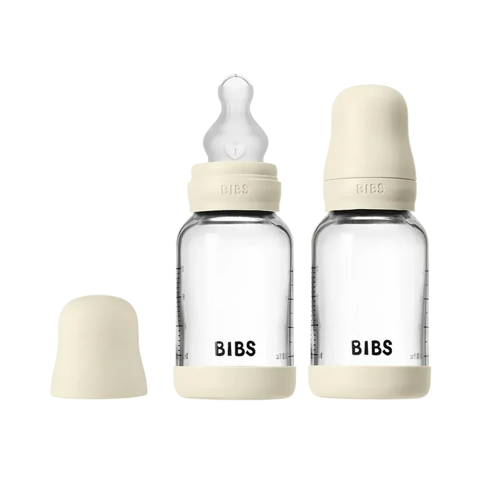 Two clear baby bottles with beige caps and 'Bibs' branding on a white background