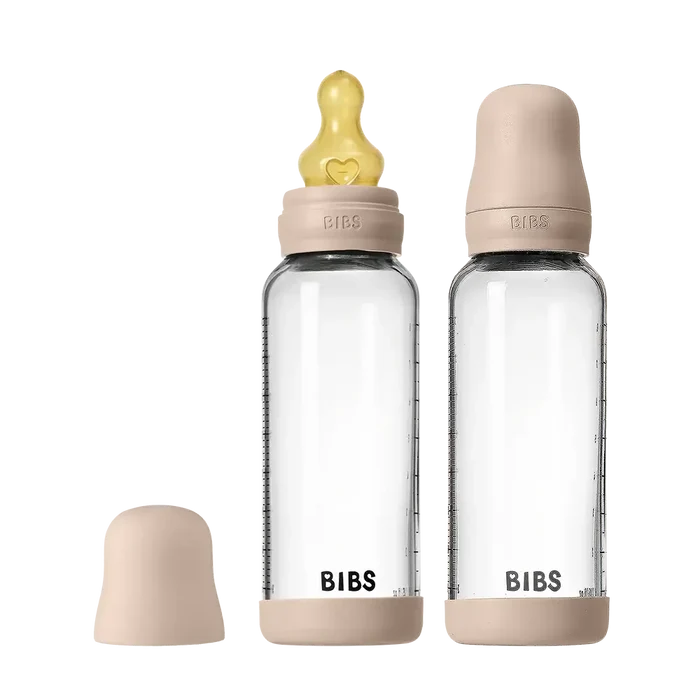 Two clear baby bottles with pink caps and nipples on a white background, branded 'Bibs'.