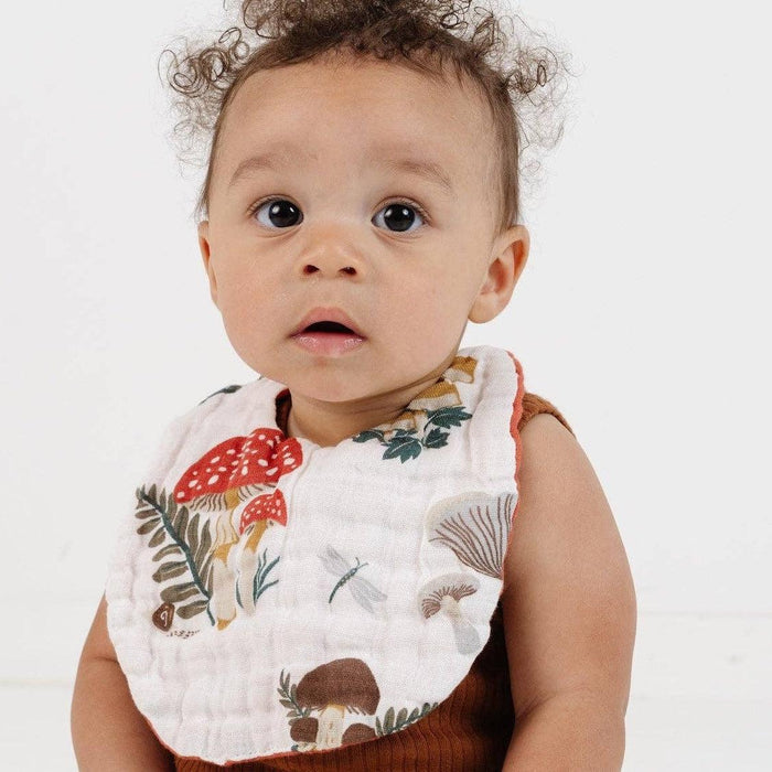 Baby wearing a floral bib and brown outfit on a white background