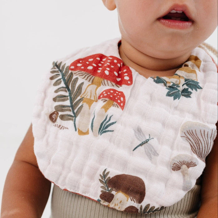 Child wearing a bib with mushroom design on a white background