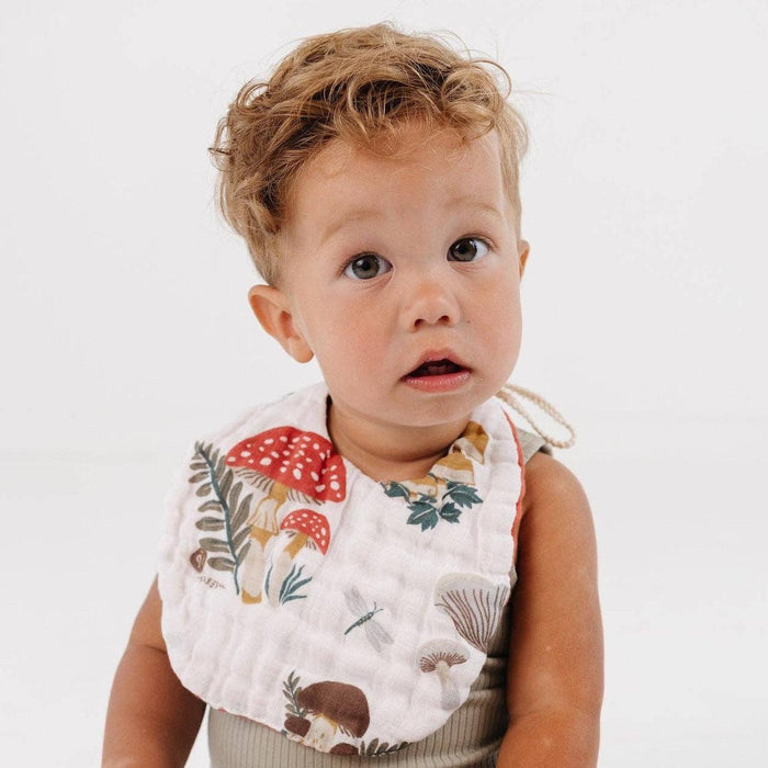 Child wearing a bib with nature-themed design on a white background