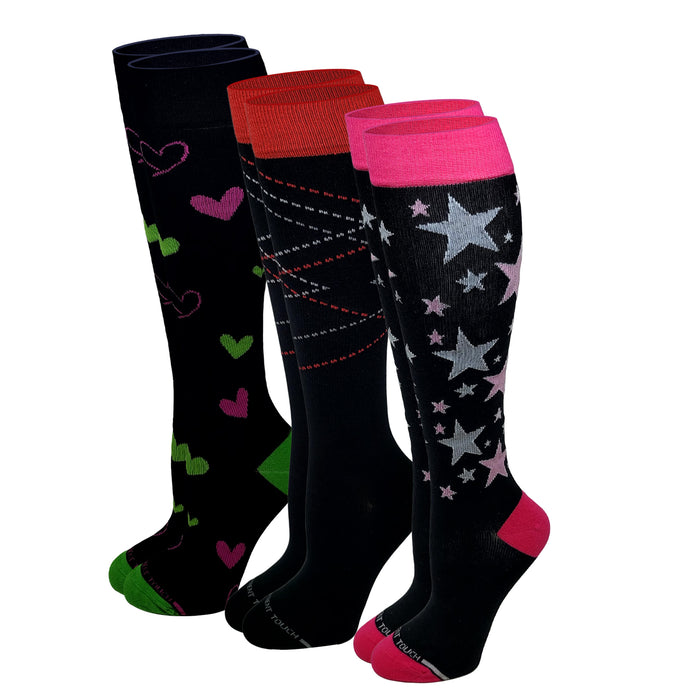 Three pairs of knee-high socks displayed together on a white background. The front pair is black with silver and pink stars, bright pink cuffs, and pink toes.