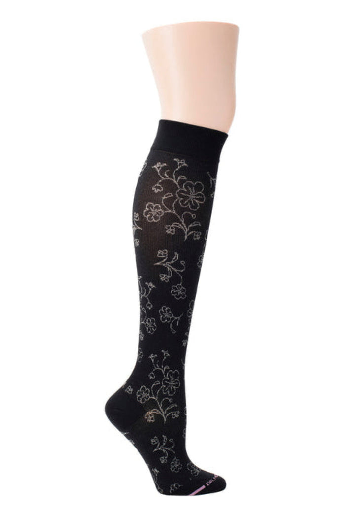 Black knee-high sock with floral pattern on a mannequin leg against a white background