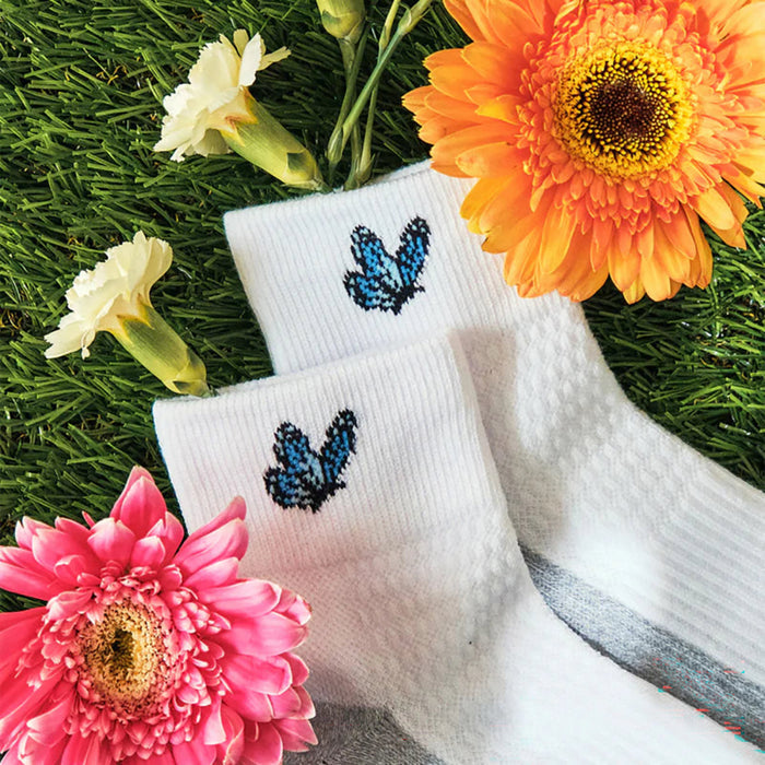 White socks with butterfly design on grass with flowers