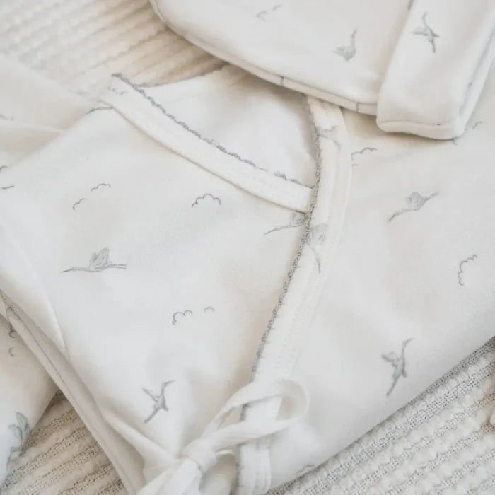 Set of light-colored baby blankets with embroidered designs on a textured surface