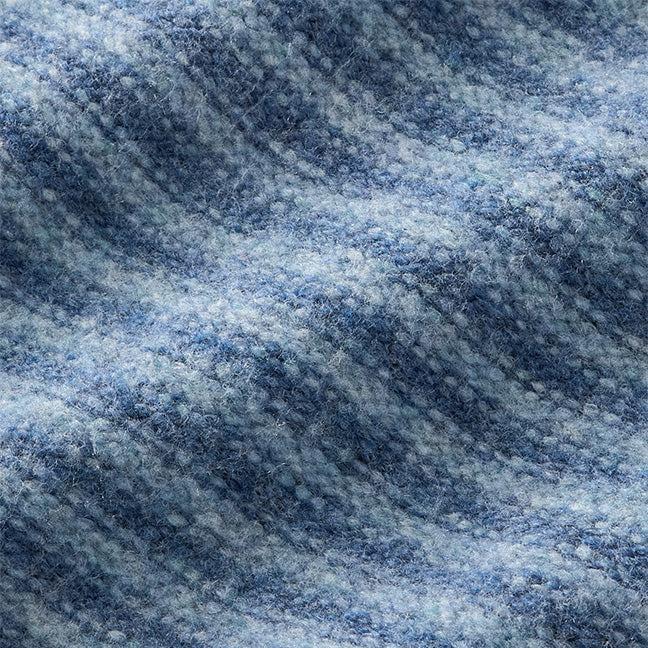 A close-up of a textured fabric with a heathered pattern of blue and white yarns, showing a soft, woven surface.
