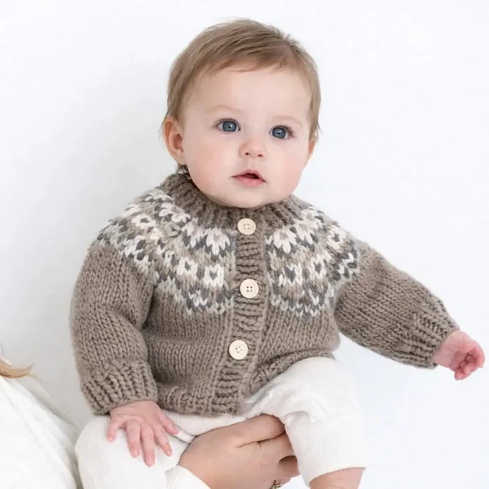 Baby wearing a knitted sweater with a patterned collar on a white background
