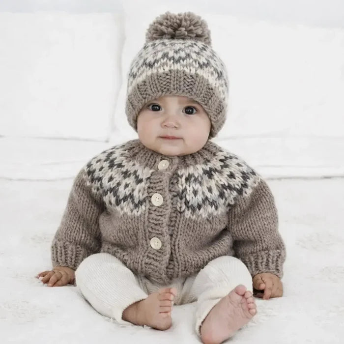 Baby wearing a knitted sweater and hat on a white background