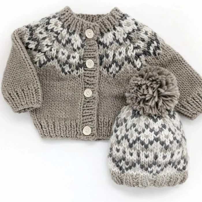 A baby knit cardigan and matching beanie set in a taupe, gray, and off-white fair isle pattern, displayed on a white background with a black banner at the top containing the text 'search fairisle to find the coordinating sweater'.