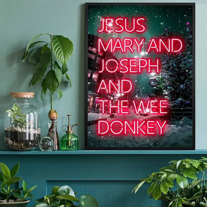 Jesus, Mary, Joseph & The Wee Donkey Christmas Print black framed on a living room shelf