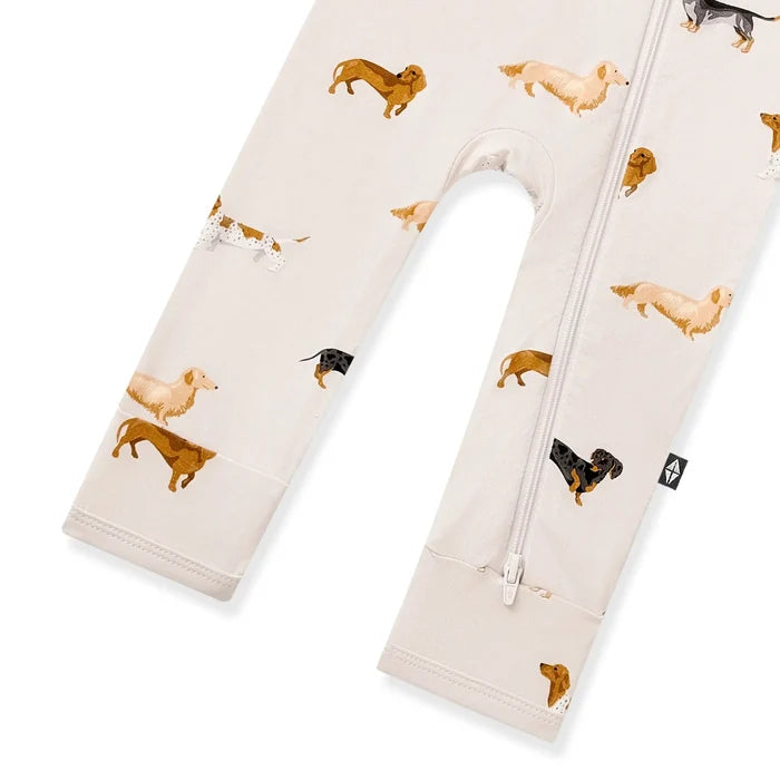 A romper with an allover print of dachshunds in black, brown, and tan, featuring a front zipper.