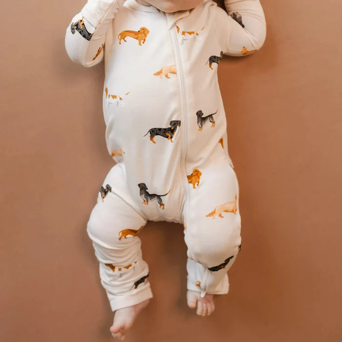 Baby wearing a white onesie with dog prints on a beige background