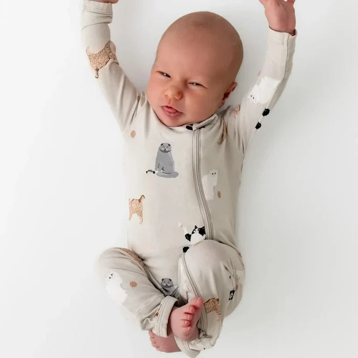 Baby in a white onesie with animal prints on a white background