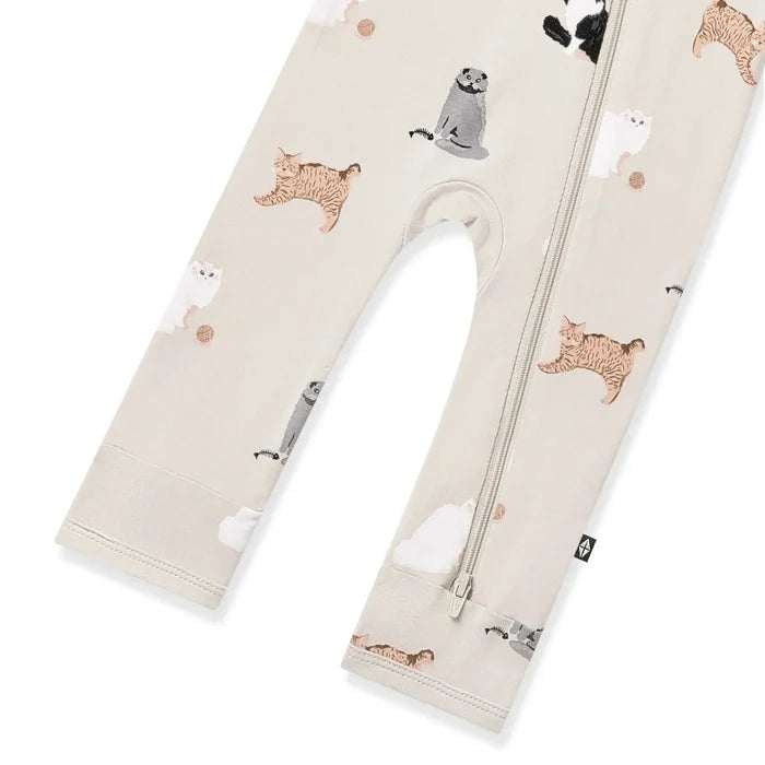 A baby romper in a light beige color, featuring an all-over print of cute cats with a front zipper.