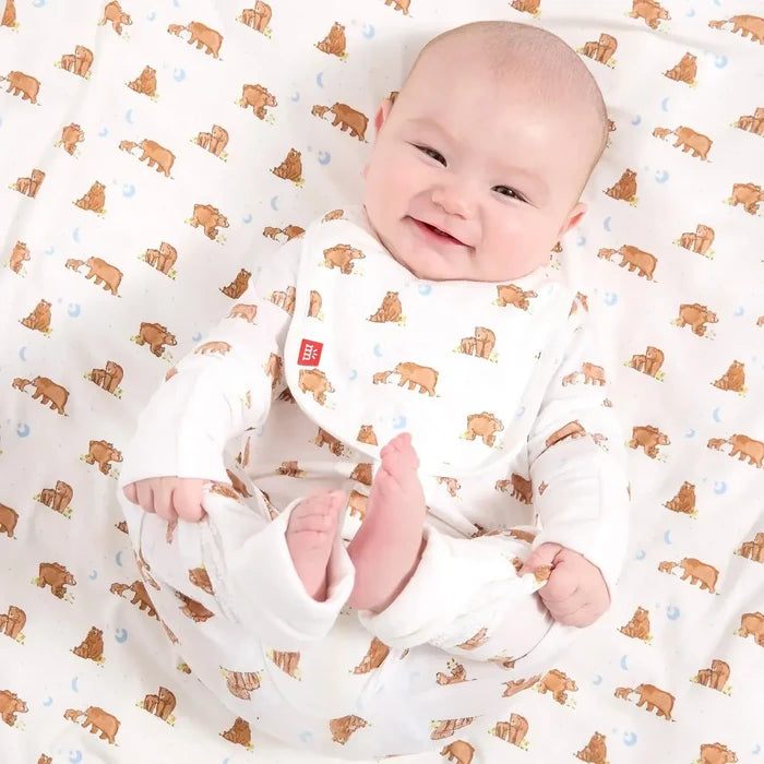 Baby in a white onesie with brown bear patterns on a matching blanket