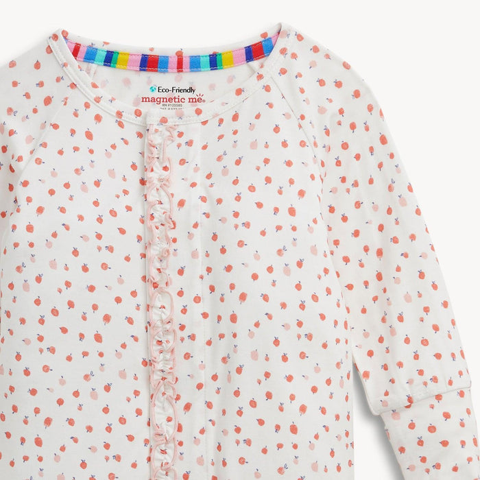 A close-up of a baby long-sleeve romper with a white base, covered in a small pink apple pattern, and a ruffled front placket.