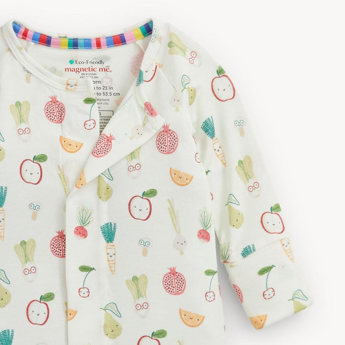 A baby long-sleeve romper with a white background and a colorful cartoon fruit and vegetable print, featuring a magentic button closure and a visible 'magnetic me.' brand label.