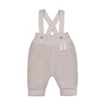 A light beige ribbed knit baby overalls with adjustable shoulder straps, decorative buttons, and a small 'My First Pet' brand label on the side, shown against a plain white background.
