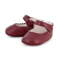 A pair of burgundy baby ballet flats with scalloped edges and adjustable straps, shown on a clean white background.