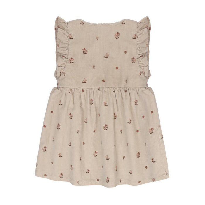 A sleeveless beige dress for toddlers or girls, featuring a small brown floral print scattered across the fabric, ruffled shoulder straps, and a gathered waistline, shown against a plain white background.