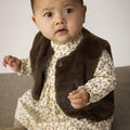 Baby wearing a floral dress with a brown vest