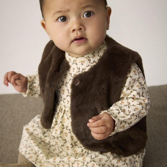 Baby wearing a floral dress with a brown vest