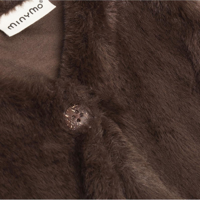 Close-up of a brown fluffy fabric with a button and Minymo label.