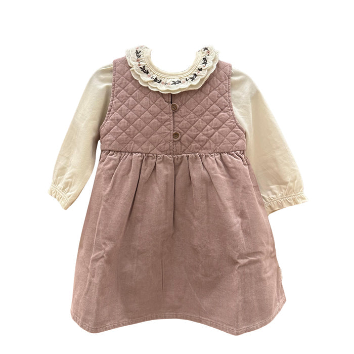 A toddler girl's long-sleeve dress featuring a dusty rose quilted vest bodice with three buttons and a cream ruffled collar with black floral embroidery, layered over a cream long-sleeve shirt.