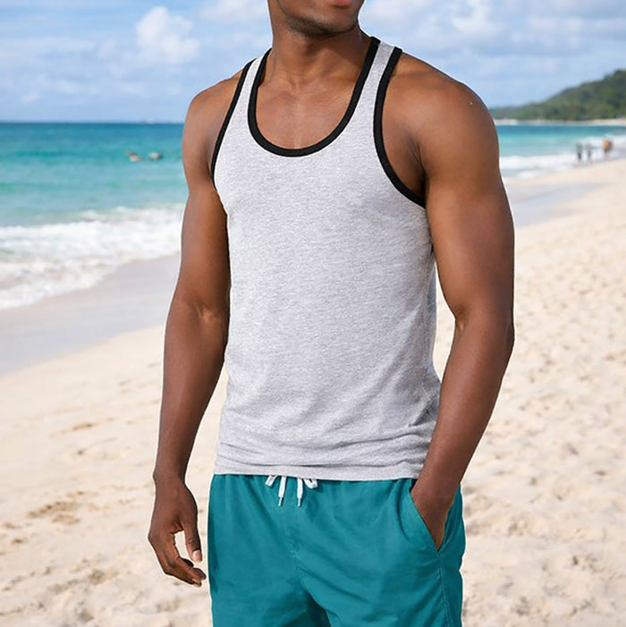 Man wearing a gray tank top with black trim and teal shorts on a beach.