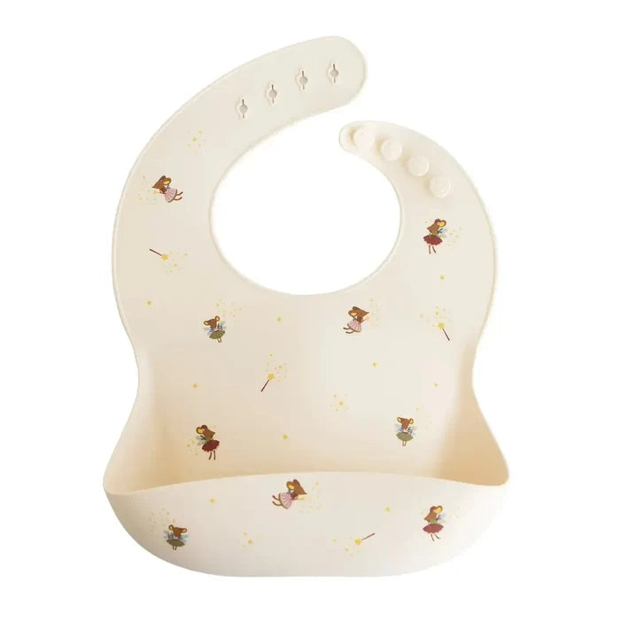 An off-white silicone baby bib with a whimsical print of fairies and gold stars, featuring a built-in suction cup at the bottom and a curved neck opening.
