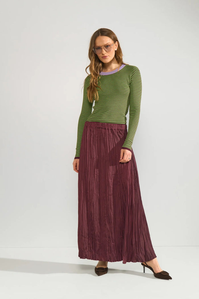 Model wearing Numph 706923 NUFILINA Pullover – Fig in green and black stripes with a lavender neckline, paired with a pleated burgundy skirt by Numph. Shop Numph at Dotique.