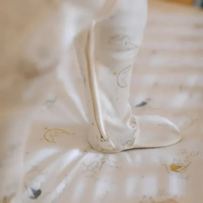 Close-up of a baby's foot in a white sock with a pattern on a light surface.