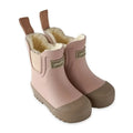 A pair of children's rain boots in dusty pink with tan rubber toe caps and pull tabs, featuring a soft cream fleece lining and a small metallic brand plaque on the side.