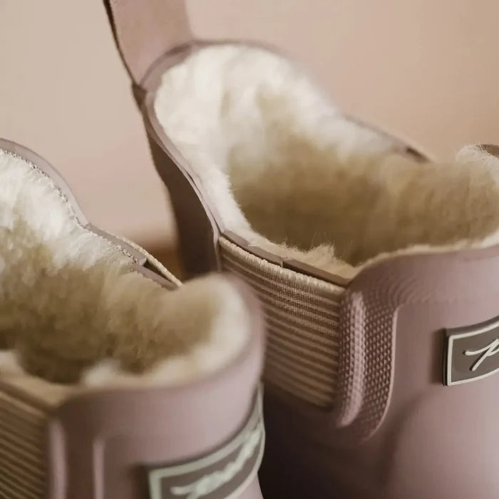 Pair of pink boots with fur lining on a beige background