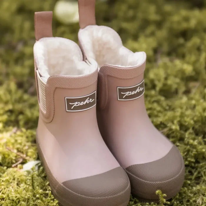 Pair of brown rubber boots with fur lining on a mossy background