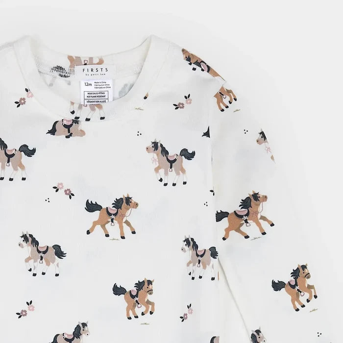 A close-up of a white long-sleeve children's top with an all-over print of cartoon horses in brown, beige, and black. The brand label 'FIRSTS for kids' is visible inside the collar.