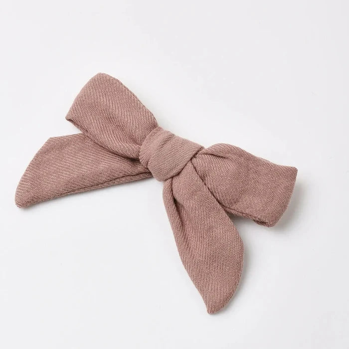 A dusty rose textured fabric bow headband, photographed flat on a clean white background.