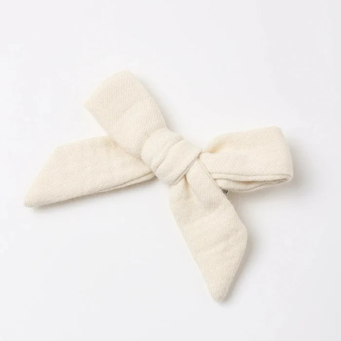 An off-white textured fabric hair tie bow, photographed on a clean white background.