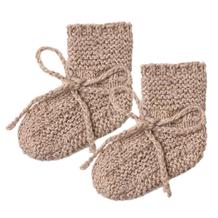 Pair of beige knitted baby booties on a white background