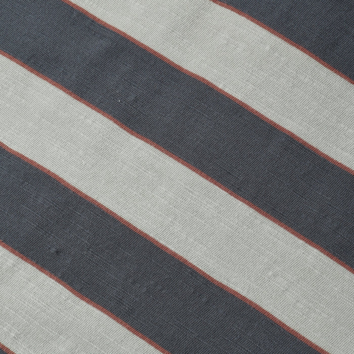 A close-up of a striped textile pattern featuring diagonal bands of dark charcoal gray, light beige, and thin rust-red lines.