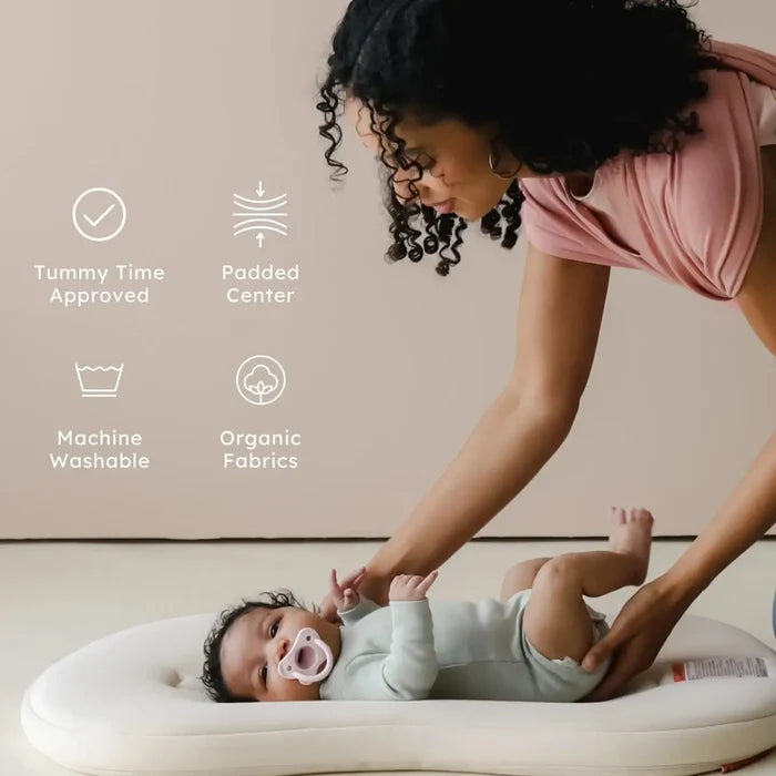 Woman attending to a baby on a cushion with product features listed.
