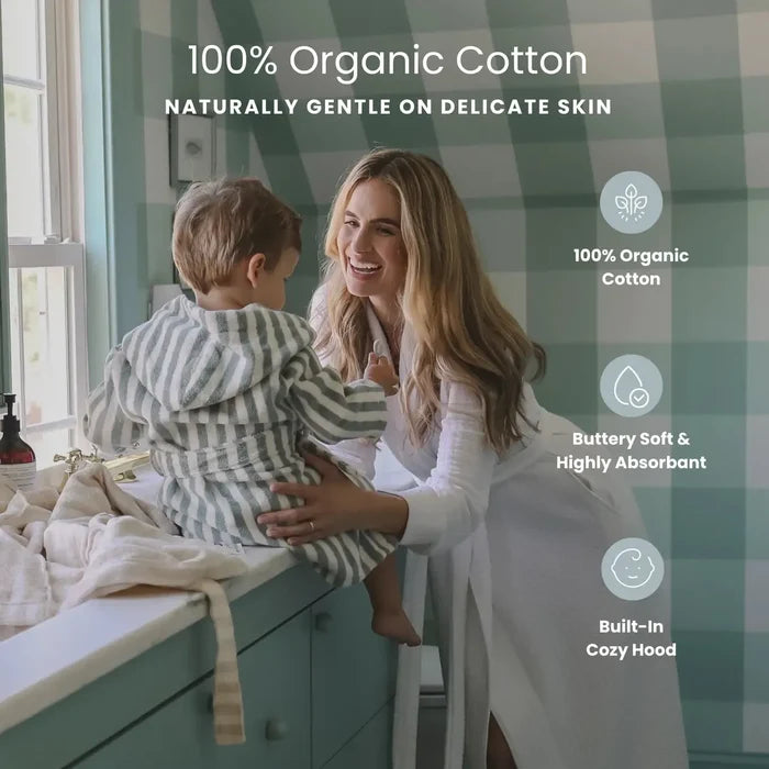 Woman sitting with child in a striped robe on a counter in a bathroom with product details listed