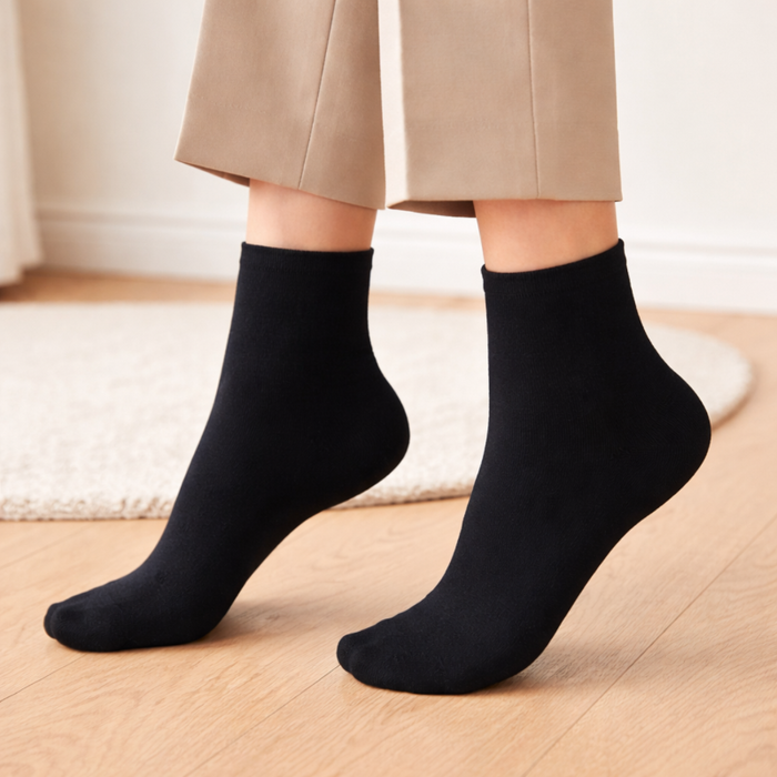 Person wearing black trouser socks on a wooden floor