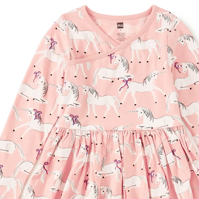 A pink long-sleeve dress with an all-over unicorn print, featuring a gathered waist and a V-neckline, shown flat against a white background.