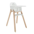A modern high chair featuring a white molded plastic seat, tray, and footrest, supported by four natural light wood legs, shown against a solid white background.