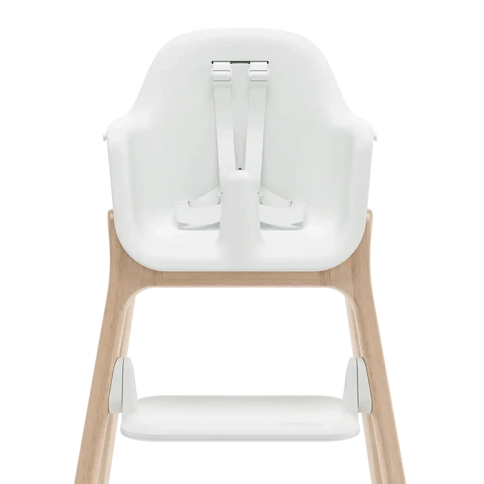 A high chair with a white molded seat and footrest, supported by a light natural wood frame, shown from the back against a solid white background.