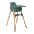 A modern high chair with a dark green molded plastic seat, tray, and footrest, supported by four natural light wood legs, shown on a solid white background.