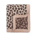 A folded knit blanket with a leopard print pattern in beige, brown, and black, featuring a solid beige fringed border.